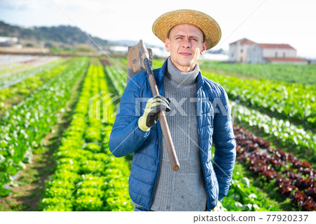 Man with gardening chopper standing outdoors 77920237