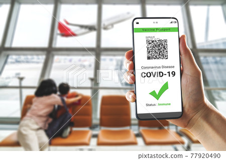 Traveler holds vaccine passport certificate to show COVID 19 vaccination status 77920490