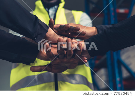 Factory workers stacking hands together in warehouse or storehouse 77920494