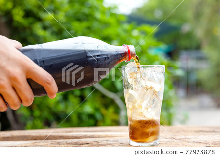 Bottle Pouring Drink In Glass On wooden table in garden 77923878