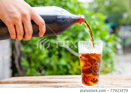 Bottle Pouring Drink In Glass On wooden table in garden 77923879