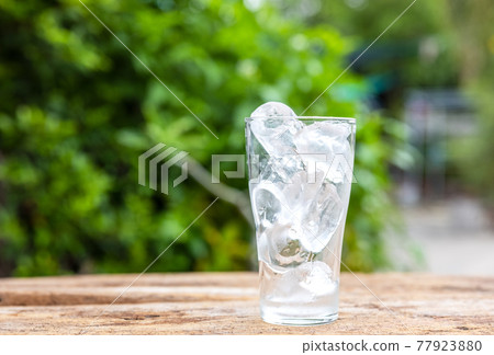 Glasses with ice cubes on wooden table nature background. 77923880