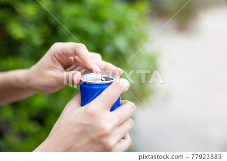 Closeup woman hand open cola can with nature background. Closeup woman hand open cola can with nature background. 77923883