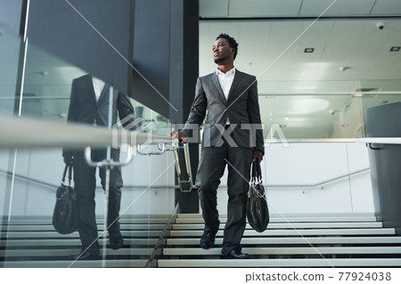 Successful African American Businessman Walking in Office Lobby Successful African American Businessman Walking in Office Lobby 77924038