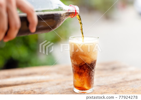 Bottle Pouring Drink In Glass On wooden table in garden 77924278