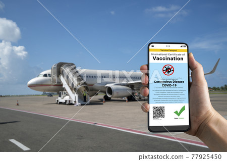 Traveler holds vaccine passport certificate to show COVID 19 vaccination status 77925450