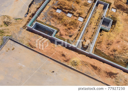 Building site of trenches dug in ground and filled with cement as foundation for future house 77927230