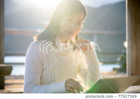 A woman worcation on the lakeside of a trip 77927569