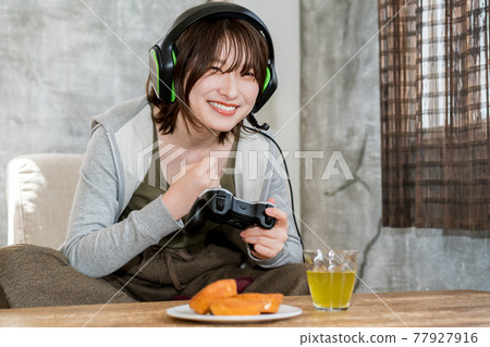 A woman playing a net game (online game) in the room 77927916