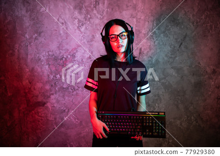 Young teen gamer wearing glasses standing posing with computer gaming equipment 77929380
