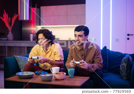 Happy male gamers playing video games at home. Happy male gamers playing video games at home. 77929569