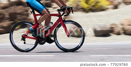 Road bike cyclist man cycling, athlete on a race cycle. Panning technique used Road bike cyclist man cycling, athlete on a race cycle. Panning technique used 77929760