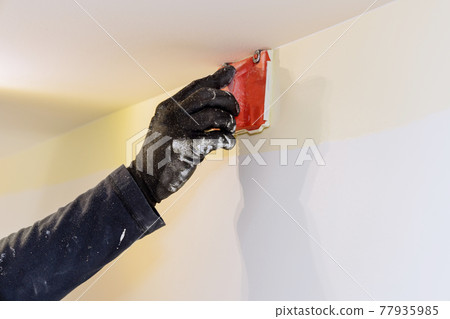 Home renovation on working contractor user in corner paint edger brush painter hands with painting the wall Home renovation on working contractor user in corner paint edger brush painter hands with painting the wall 77935985
