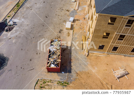 Aerial view of apartment framing of a new house under wooden boards the construction trash dumpsters Aerial view of apartment framing of a new house under wooden boards the construction trash dumpsters 77935987