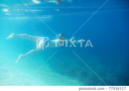 Woman swimming underwater 77936317