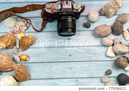 camera and seashells on a blue wooden background.Marine theme 77936622