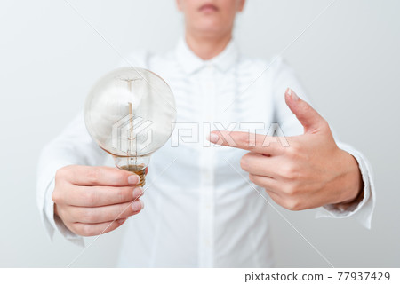 Lady Pointing To Lamp Held In Hand In Formal Outfit Presenting New Ideas For Project, Business Woman Carying Bulb Exhibiting Lately Released Technologies, Lightbulb Veiwing Fresh Idea 77937429