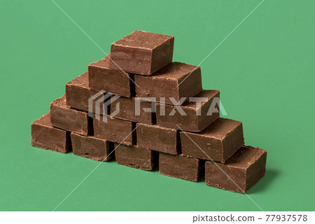 Chocolate fudge pile isolated on a green background. 77937578