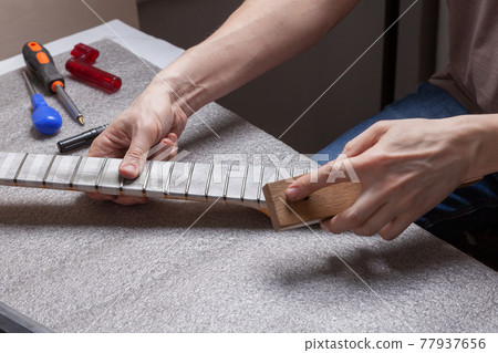 Guitar technician repairing the neck of a guitar. 77937656
