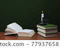 open blank book and stack of books with burning candles on green background 77937658