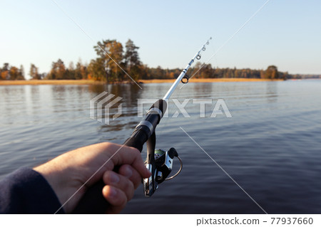 fishing rod in hand on the background of the autumn island 77937660