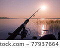 fishing rod against the backdrop of a deserted calm pink sunset 77937664