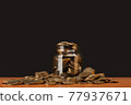 scattered money in a glass jar on the table. 77937671