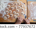 the process of handmade dumplings on a wooden board. 77937672