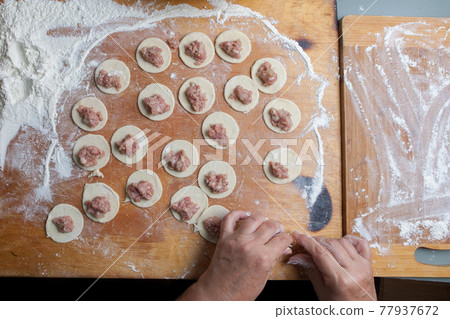 the process of handmade dumplings on a wooden board. 77937672