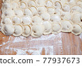 homemade dumplings with meat on a floured board. 77937673