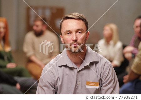 Serious middle aged man sitting against patients sharing their problems 77938271