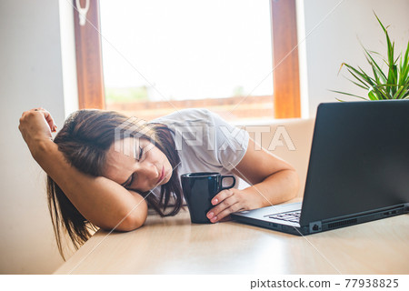 Tired businesswoman sleeping on table in office. Young exhausted girl working from home. Tired businesswoman sleeping on table in office. Young exhausted girl working from home. 77938825