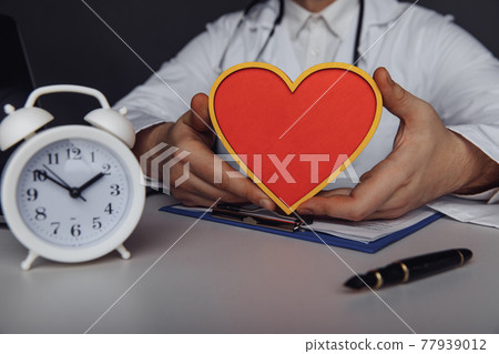 Healthcare and treatment concept. Doctor showing a wooden model of heart in his office Healthcare and treatment concept. Doctor showing a wooden model of heart in his office 77939012