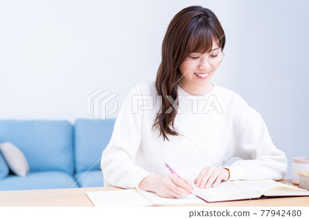戴眼鏡在客廳學習的年輕女子 戴眼鏡在客廳學習的年輕女子 77942480