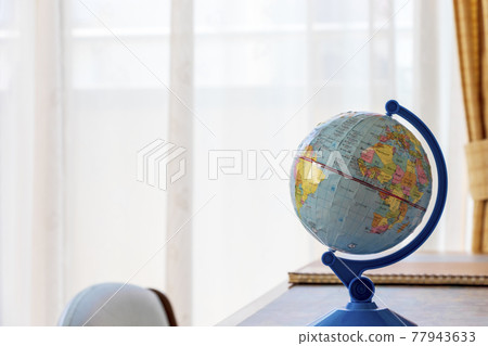 A small globe placed on a desk 77943633
