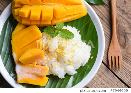 Ripe mango rice cooked with coconut milk, Sticky rice summer tropical fruit food Asian Thai dessert sweet mango peel and sliced on plate and fresh mint leaves 77944609