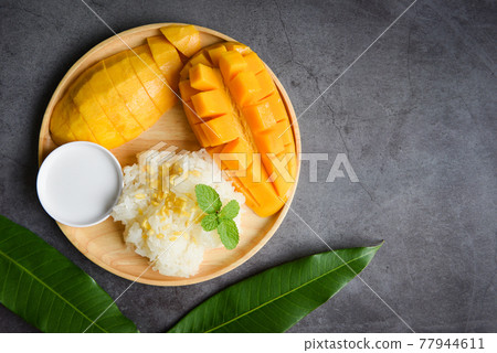 Ripe mango rice cooked with coconut milk, Sticky rice summer tropical fruit food Asian Thai dessert sweet mango peel and sliced on plate and fresh mint leaves 77944611