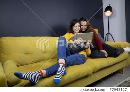 young lesbian couple make purchases or payments online lying on sofa young lesbian couple make purchases or payments online lying on sofa 77945127