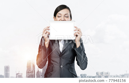 Woman with closed eyes holding tablet computer Woman with closed eyes holding tablet computer 77948156