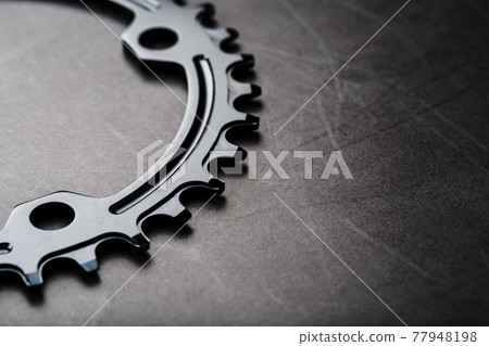A black bicycle driving star with contrasting repeating cogs on a dark background 77948198