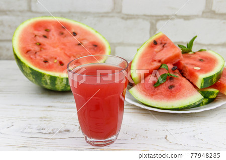 Glass of fresh watermelon juice on a white wooden table Glass of fresh watermelon juice on a white wooden table 77948285