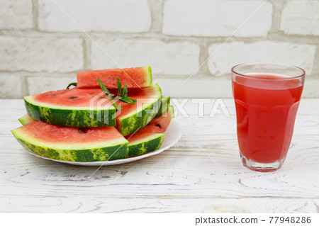 Glass of fresh watermelon juice on a white wooden table Glass of fresh watermelon juice on a white wooden table 77948286