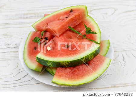 Fresh ripe sliced watermelon in white plate on a white wooden table Fresh ripe sliced watermelon in white plate on a white wooden table 77948287