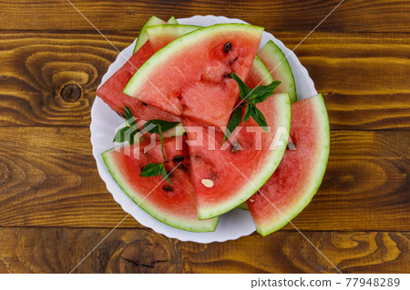Fresh ripe sliced watermelon in white plate on a wooden table. Top view Fresh ripe sliced watermelon in white plate on a wooden table. Top view 77948289