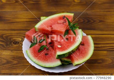 Fresh ripe sliced watermelon in white plate on a wooden table Fresh ripe sliced watermelon in white plate on a wooden table 77948290