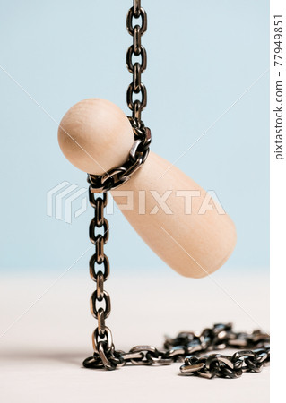 A wooden figure with a chain around his neck hanged on a blue background. Suicide concept. 77949851