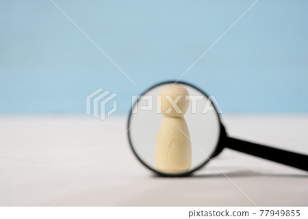 Wooden figures of people under magnifying glass on blue background. Wooden figures of people under magnifying glass on blue background. 77949855