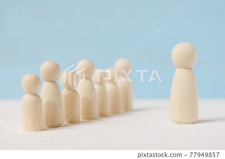 Wooden faceless figures of man in the center and people behind him. Wooden faceless figures of man in the center and people behind him. 77949857