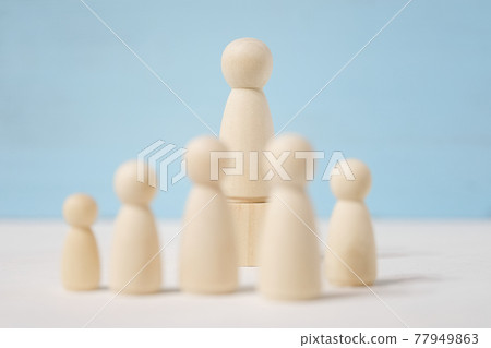 Wooden figures of man on toy block and people before him. 77949863