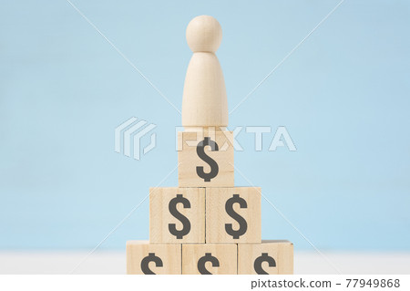 Wooden figure of man on toy blocks with painted dollar signs. Wooden figure of man on toy blocks with painted dollar signs. 77949868